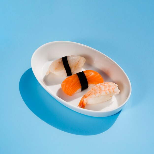 White oval bowl with sushi on a blue background