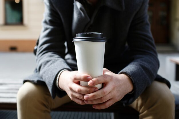 白い紙のカップは、人間の腕の中に行くコーヒー