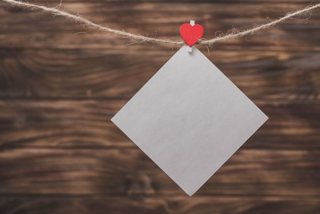 White paper hanging from a rope with a clip with a heart