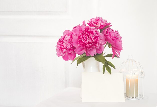 White paper for invitation text and peonies in a vas