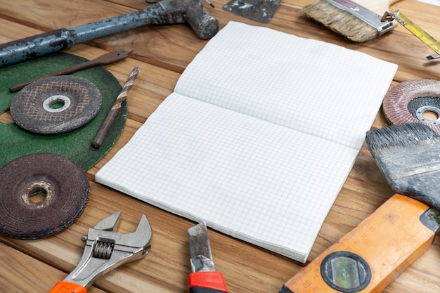 Foto gratuita libro bianco e set di utensili manuali sul pavimento di legno.