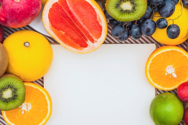 Free photo white paper with colorful citrus fruit; grapes and kiwi