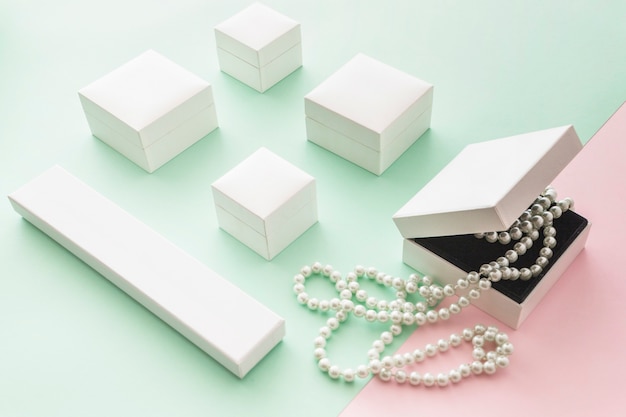 ピンクとグリーンのパステルの背景に白い箱が入った白い真珠のネックレス