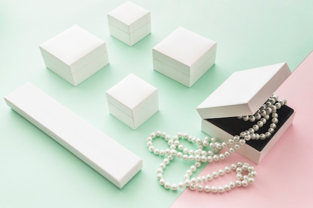 White pearls necklace with white boxes on pink and green pastel backdrop