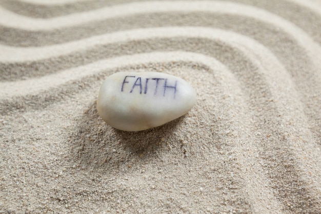 White pebble with engraved message faith