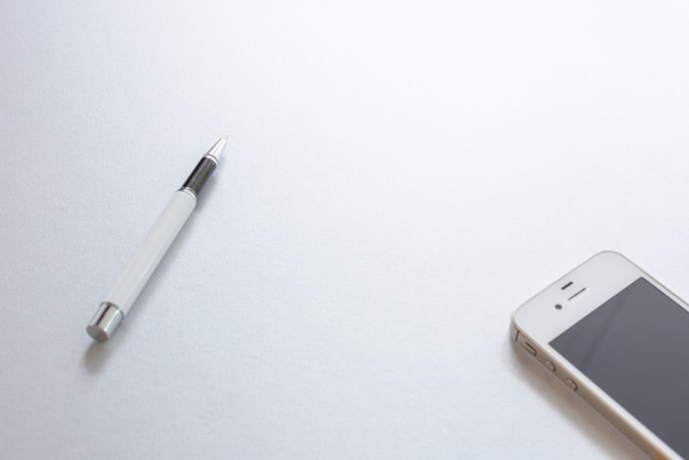 Белая ручка и белый телефон на белом фоне.