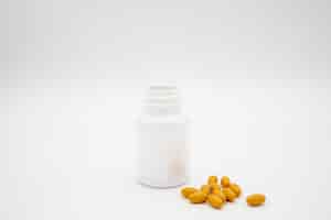 Free photo white pill bottle and orange pills against a white background