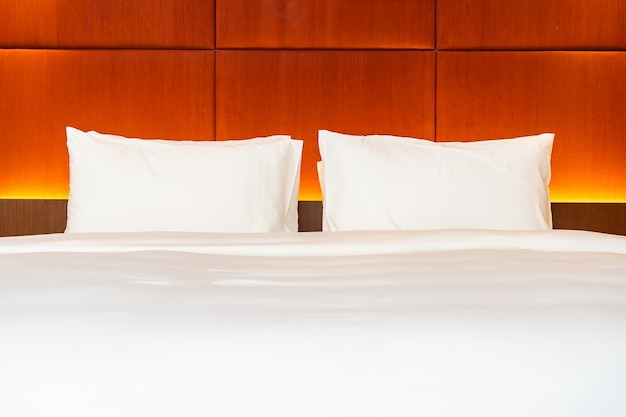 Белая подушка и одеяло на кровати с легкой лампой, украшающей интерьер спальни