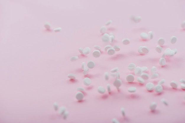 Белые таблетки на розовом фоне