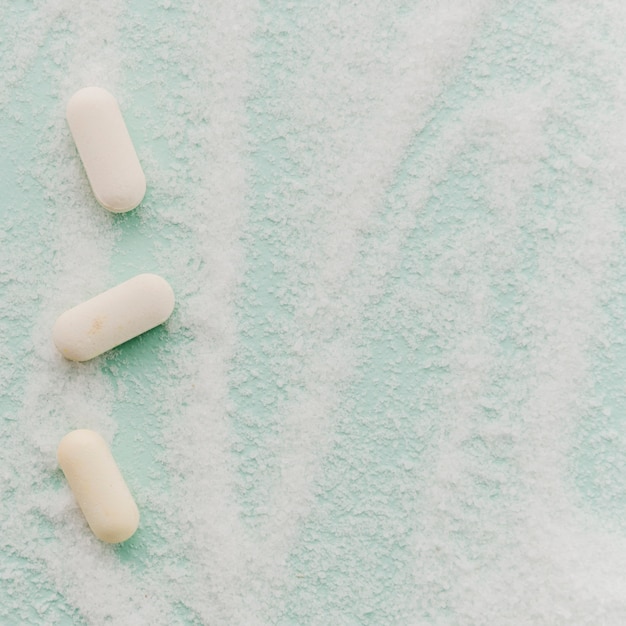 Белые таблетки по соли на фоне мятно-зеленого