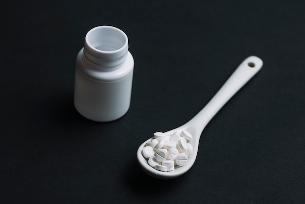 Free photo white pills on spoon and plastic bottle