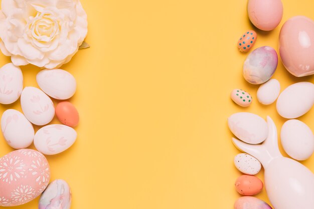 White and pink easter eggs with beautiful rose on yellow background