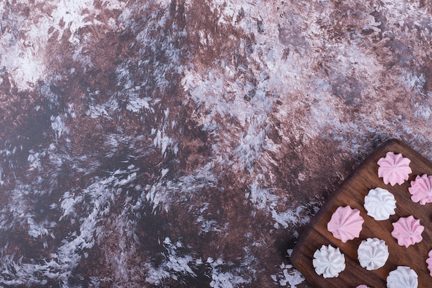 White and pink flower shaped marshmallows on a wooden platter in bottom corner.