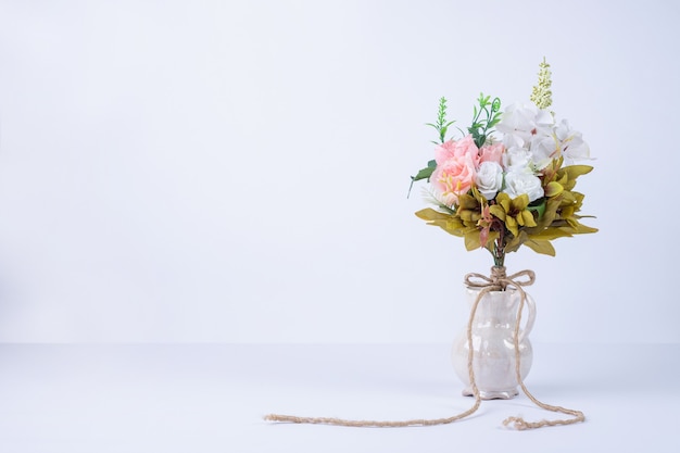 White and pink flowers in ceramic vase on white.