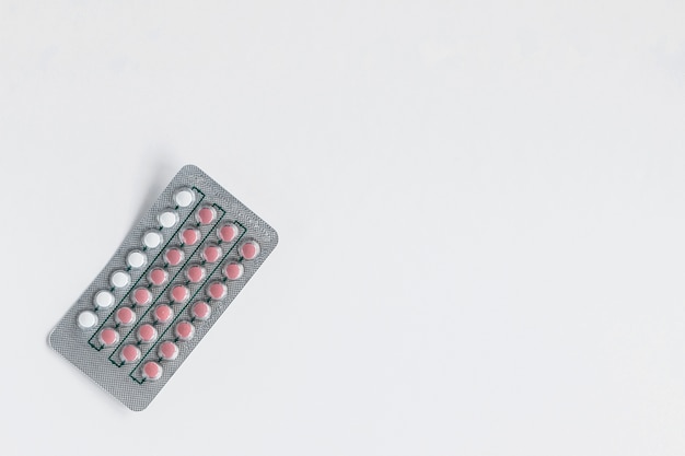 White and pink pills blister on white background