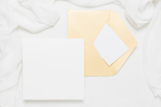 White placard near yellow envelope with scarf on white backdrop