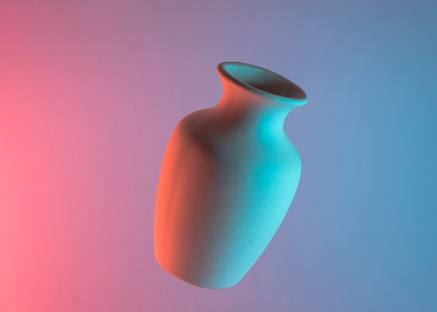 White plain ceramic vase in air against colored blue and pink backdrop