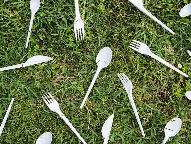 公園で緑の芝生の上の白いプラスチック製カトラリー