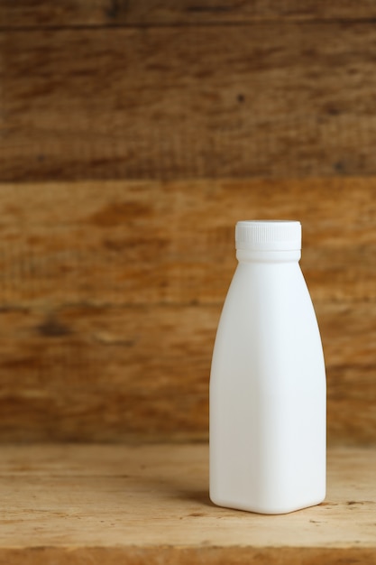 無料写真 レトロな木製テーブルの背景に白いプラスチックのミルクボトル