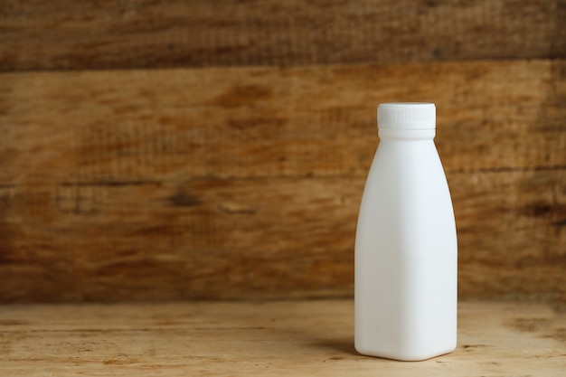 Free photo white plastic milk bottles on retro wooden table background