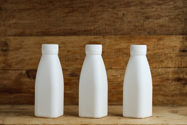 white plastic milk bottles on retro wooden table background