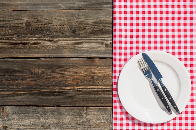 White plate on checkered table cloth and wooden textured plank