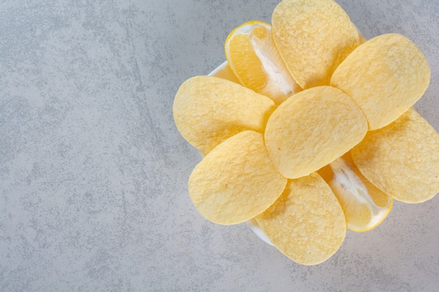 A white plate of crunchy potato chips on gray.