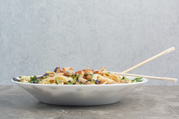 White plate of delicious macaroni with chopsticks.