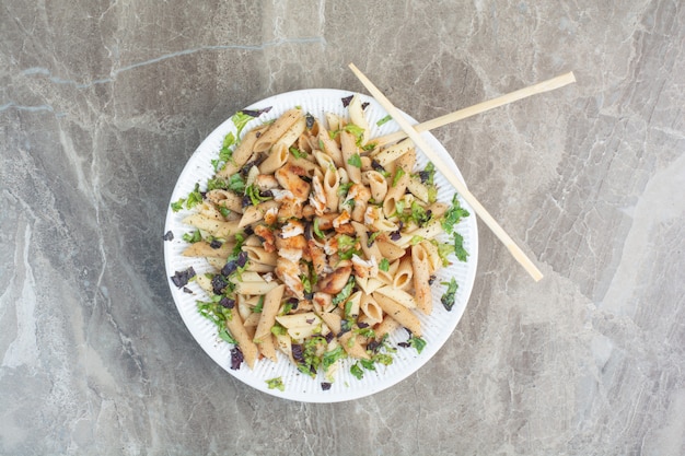 White plate of delicious macaroni with chopsticks