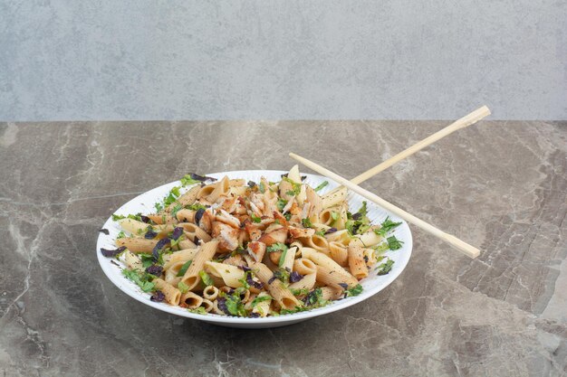 White plate of delicious macaroni with chopsticks.