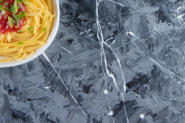 Foto gratuita piatto bianco di deliziosi spaghetti con salsa di pomodoro sulla superficie in marmo.