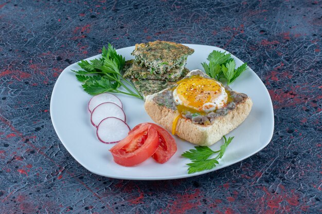 A white plate of delicious toast with meat and vegetables.