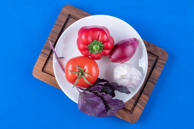 木の板に新鮮な熟した野菜の白いプレート。