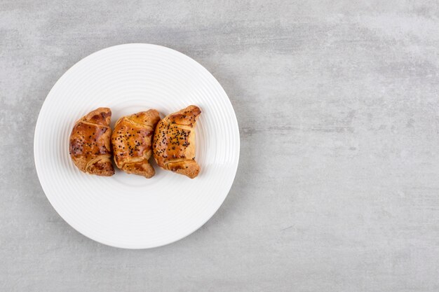 White plate of fresh tasty pastries on stone table. 