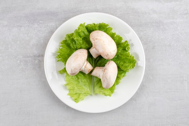 White plate of fresh white mushrooms on stone table. 