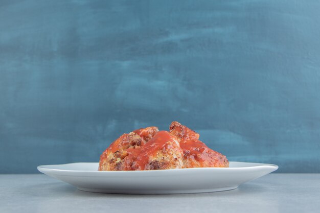 A white plate of fried meat in tomato sauce . 