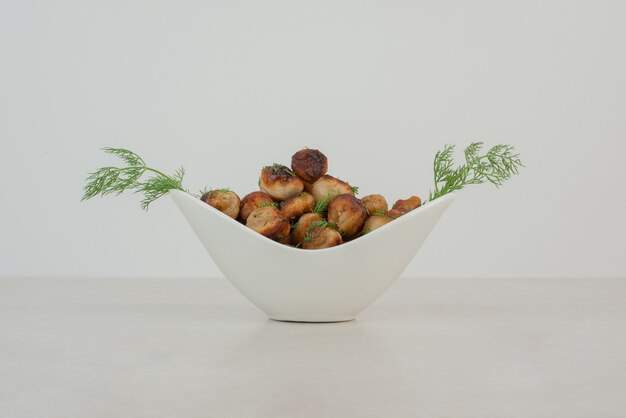 White plate of fried potato with greens.