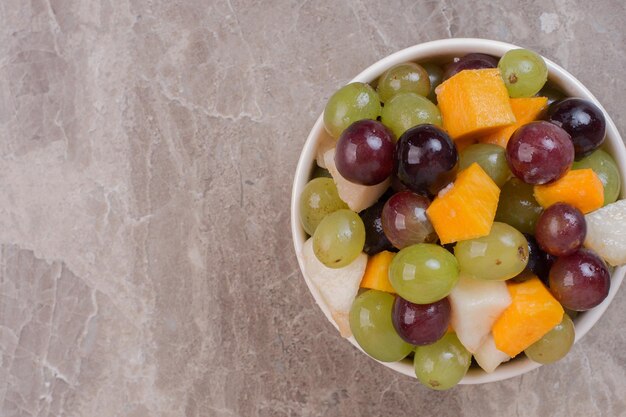 White plate of fruits on marble table.