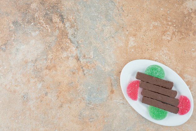 A white plate full of cookies and marmalade on marble background