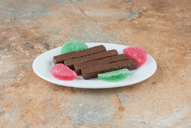 A white plate full of cookies and marmalade on marble background