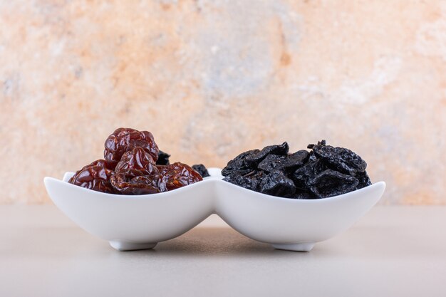 White plate full of dried tasty plums on white background. High quality photo