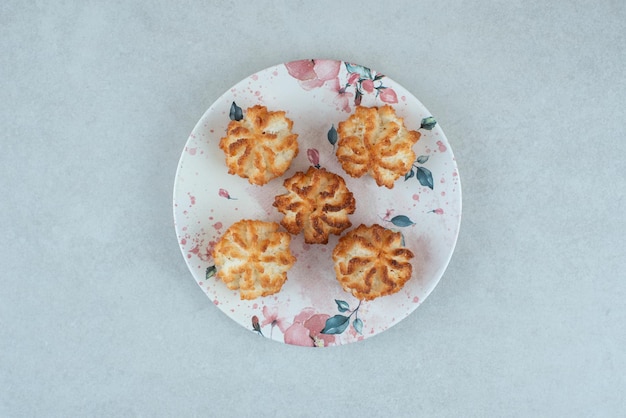 Foto gratuita un piatto bianco pieno di biscotti dolci rotondi sul tavolo bianco.