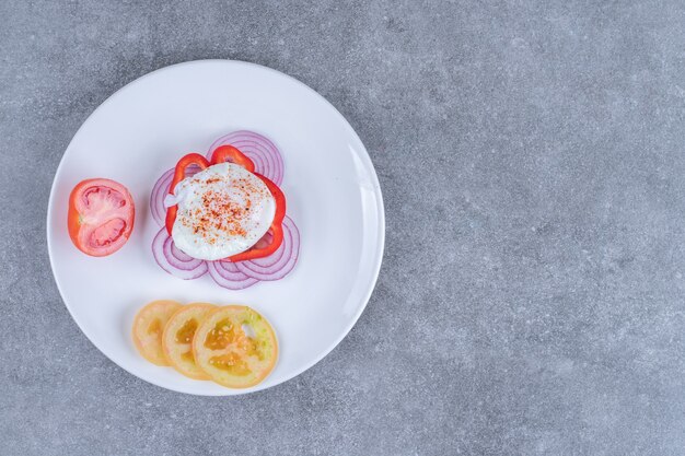 スライスした野菜とゆで卵がたっぷり入った白いお皿。高品質の写真