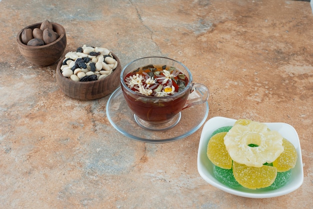 A white plate full of sugar jelly candy and cup of herbal tea