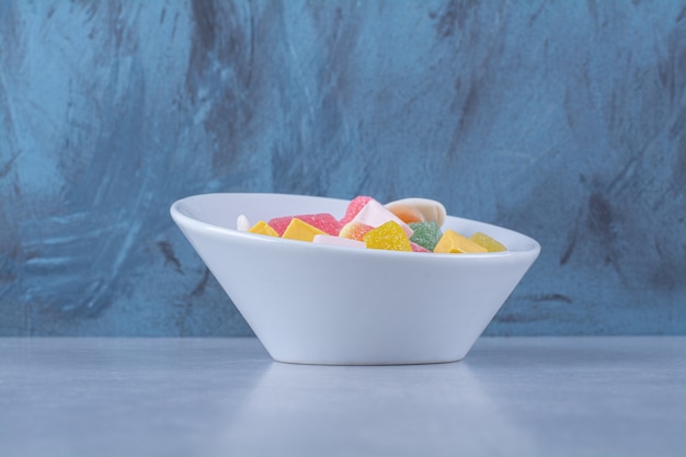 A white plate full of sugary jelly candies on gray surface 