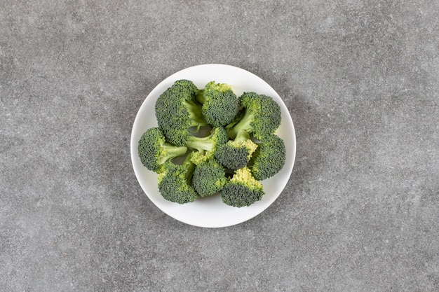 White plate of healthy fresh broccoli on stone background.