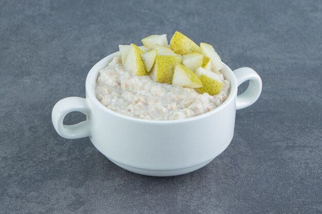 A white plate of oatmeal porridge with slices of pear .