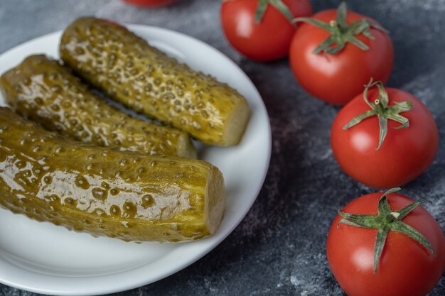 토마토와 절인 된 오이의 흰색 접시.