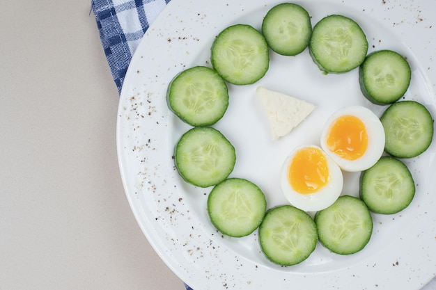 A white plate of sliced cucumber and boiled egg .