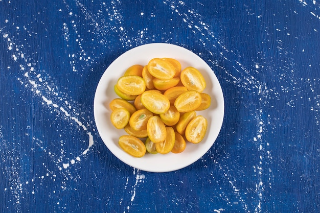 Foto gratuita piatto bianco di frutti di kumquat a fette sul tavolo di marmo.